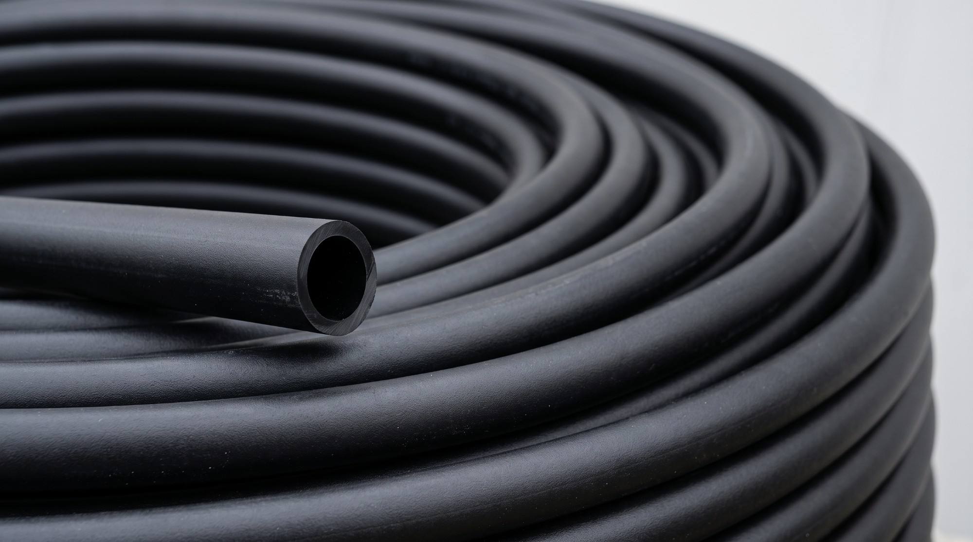 A coil of black HDPE pipe with one cut end in front